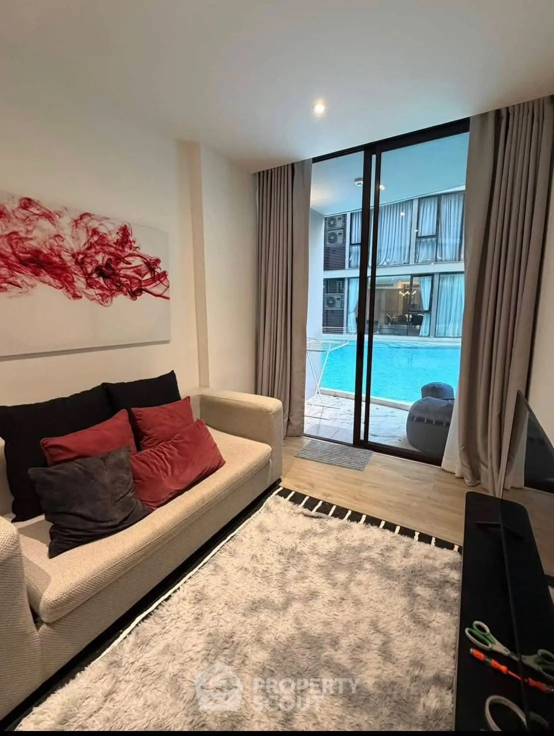 Modern living room with pool view, featuring cozy sofa and stylish decor in a luxurious apartment.