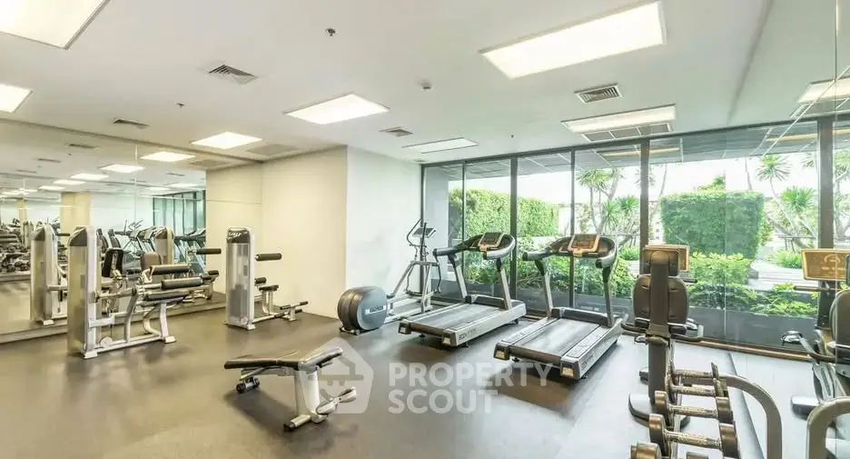 Modern gym with state-of-the-art equipment and large windows overlooking greenery.
