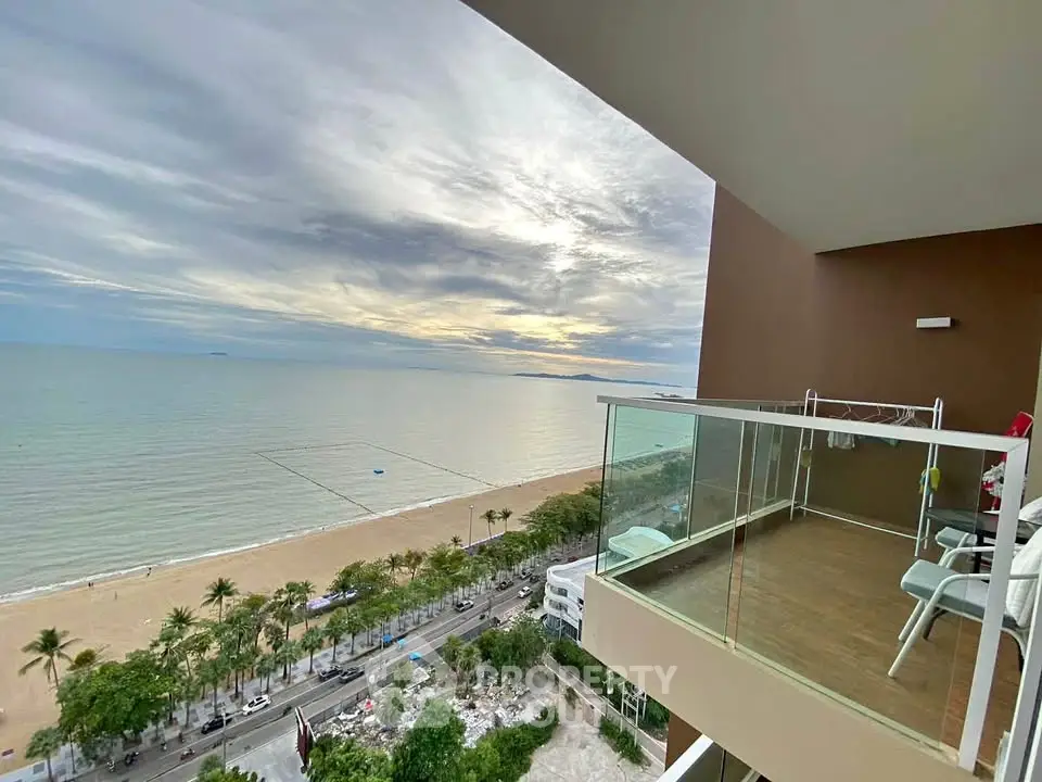 Stunning beachfront balcony view with expansive ocean and sandy beach panorama.
