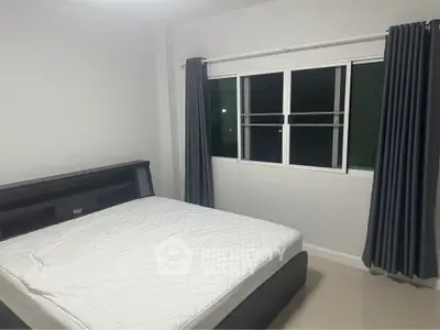 Spacious bedroom with large window and modern furnishings