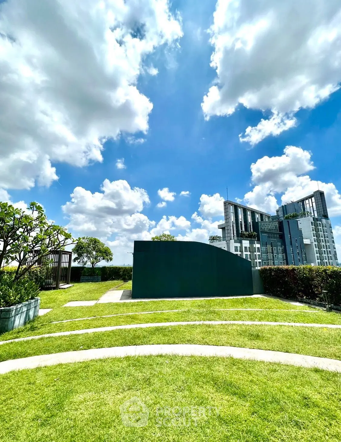 Stunning rooftop garden with lush greenery and city skyline views under a bright blue sky.