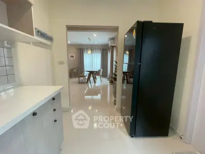 Modern kitchen with sleek black fridge and open layout leading to a bright dining area.
