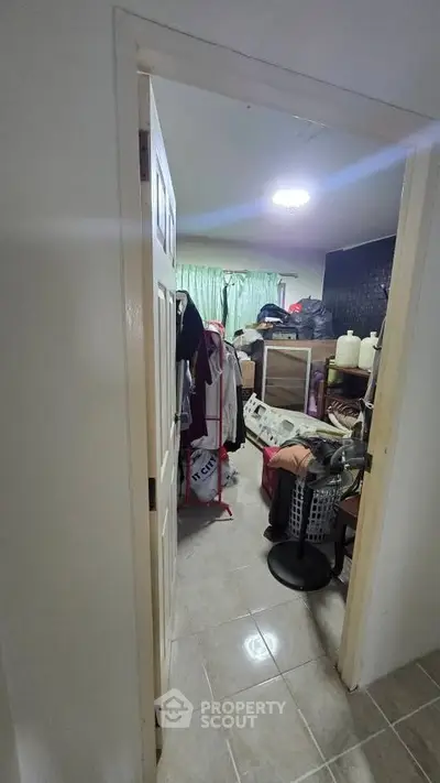 Cluttered storage room with various items and tiled floor