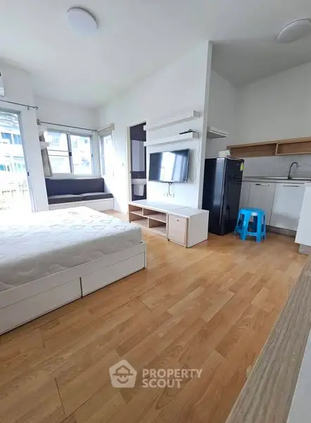 Modern studio apartment with wooden flooring and compact kitchen