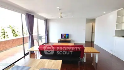 Spacious living room with red sofa and balcony view, perfect for relaxation.