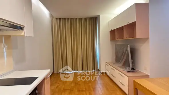 Modern apartment interior with sleek kitchen and cozy living area featuring wooden flooring and stylish cabinetry.