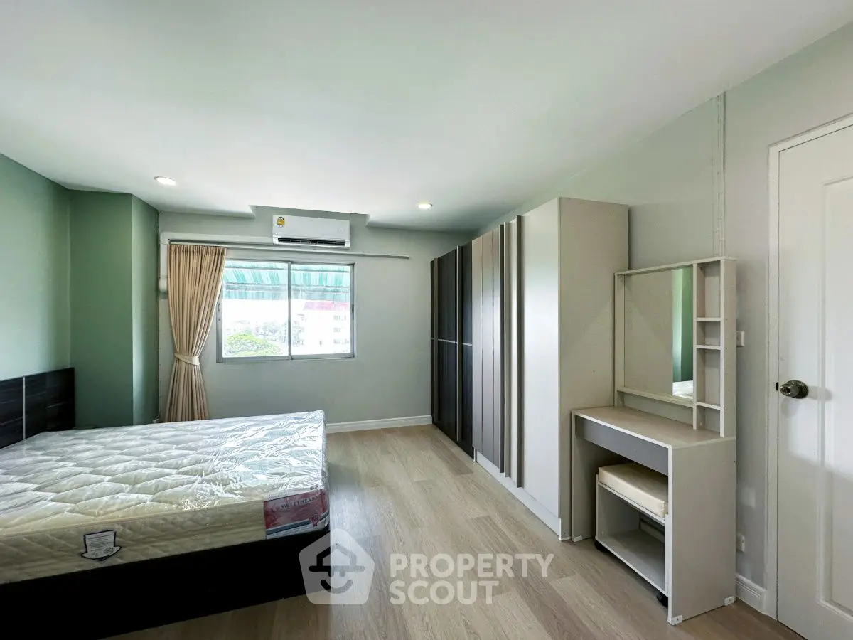 Spacious bedroom with large window and modern furnishings