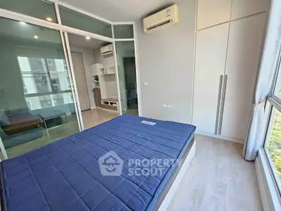 Modern bedroom with large window and built-in wardrobe in a stylish apartment.