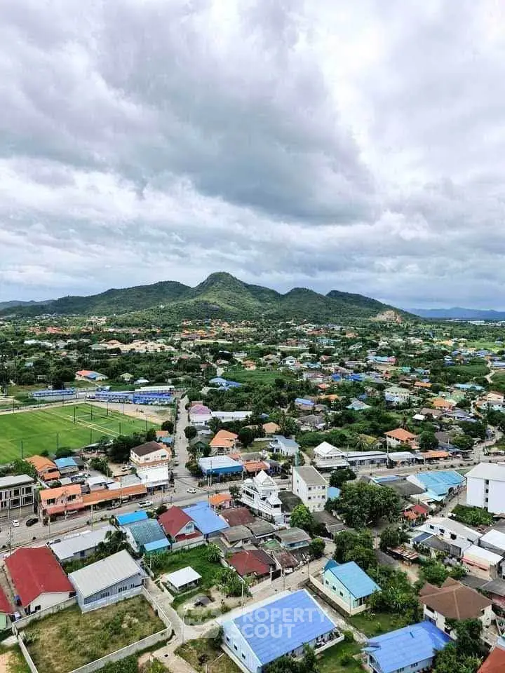 Scenic aerial view of a vibrant residential neighborhood with lush green hills in the background.