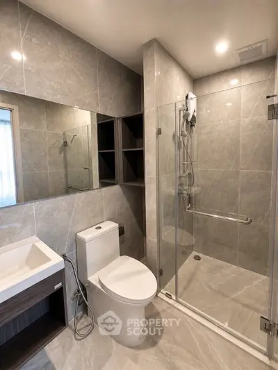 Modern bathroom with sleek design, featuring a glass shower enclosure and elegant fixtures.