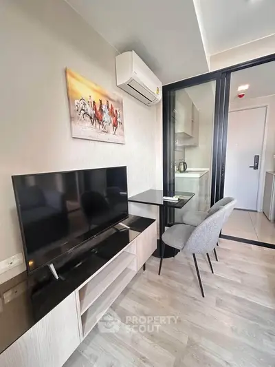 Modern living room with sleek TV setup and stylish dining area in a compact apartment.