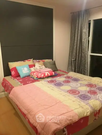 Cozy bedroom with colorful bedding and large window for natural light.