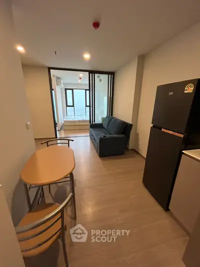Modern apartment interior with cozy living room and dining area, featuring a sofa and compact dining table.