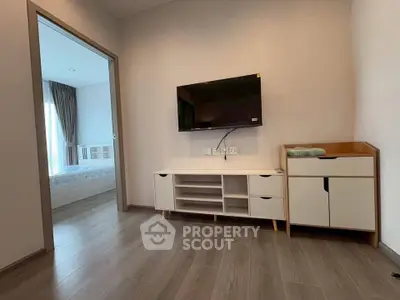 Modern living room with sleek TV setup and view into a cozy bedroom