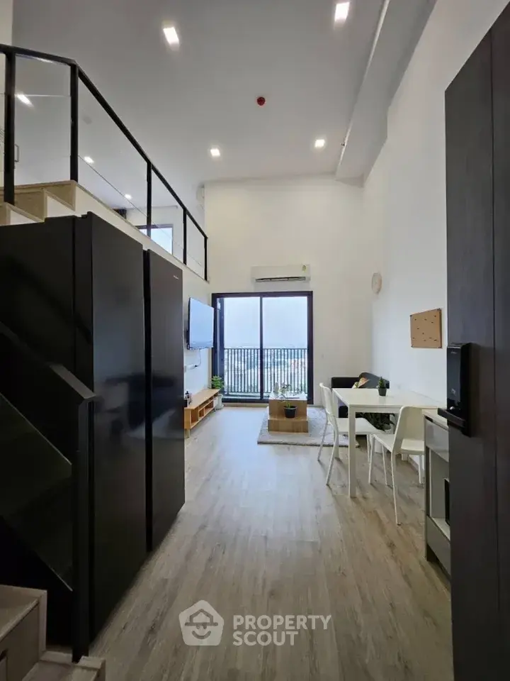 Modern loft-style living room with high ceilings and balcony view