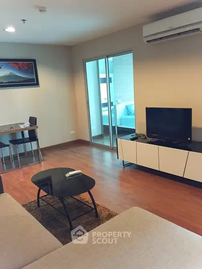 Modern living room with sleek furniture and air conditioning, featuring a cozy seating area and a view into the bedroom.