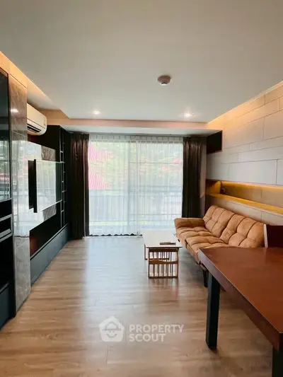 Spacious living room with modern decor and large window offering natural light.