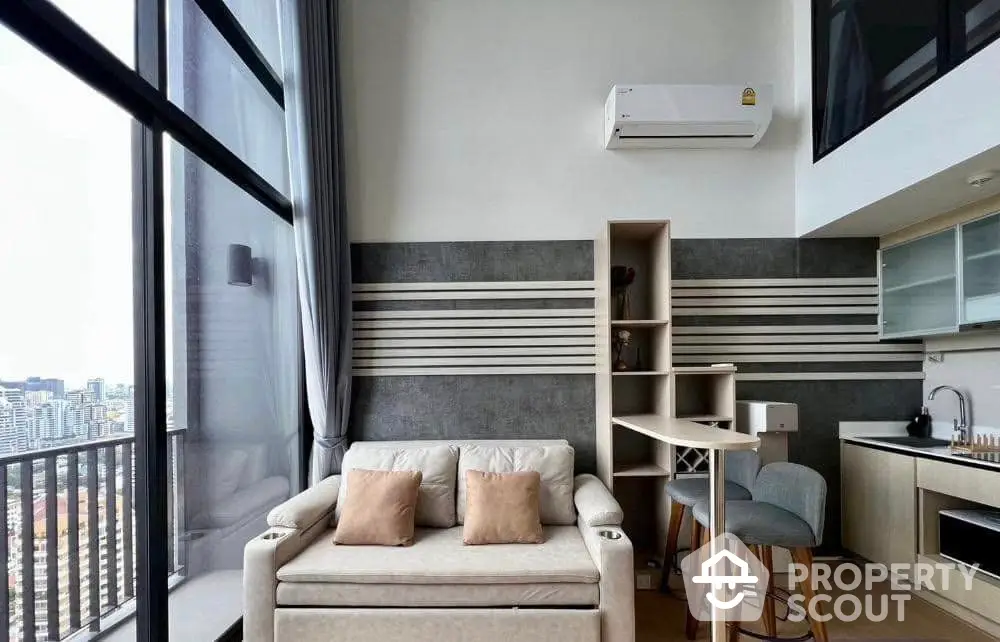 Modern loft apartment with high ceilings and city view, featuring cozy living area and compact kitchen.