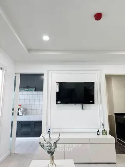 Modern living room with wall-mounted TV and sleek kitchen view