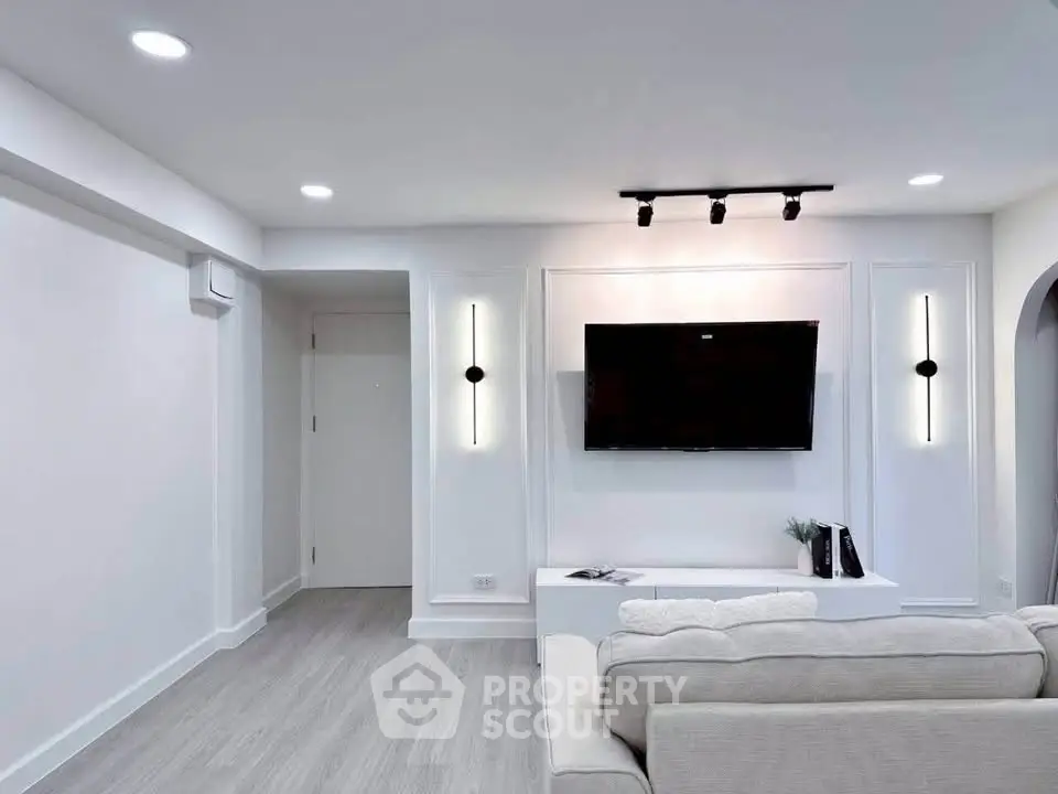 Modern living room with sleek design, wall-mounted TV, and elegant lighting fixtures.