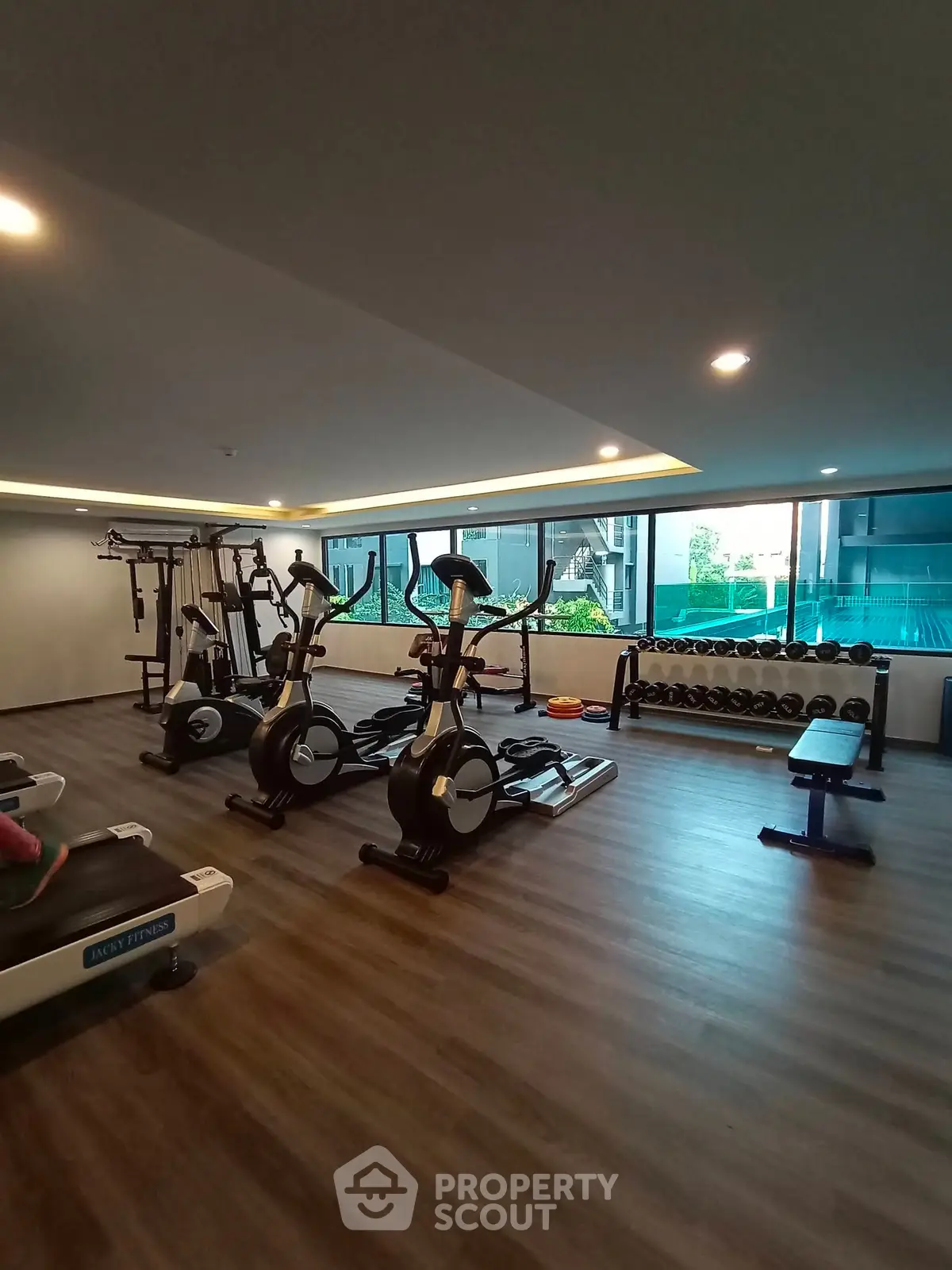 Modern gym with exercise equipment and large windows in a residential building.