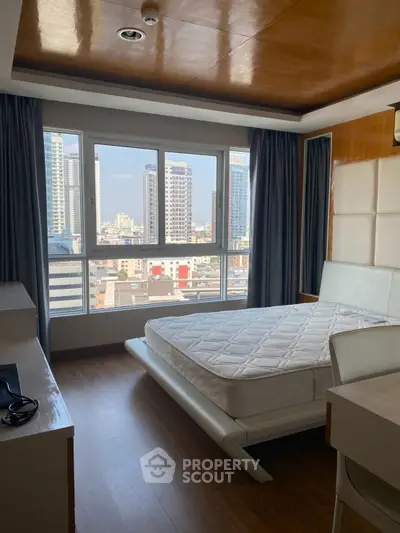 Modern bedroom with city view, featuring sleek furniture and large windows.