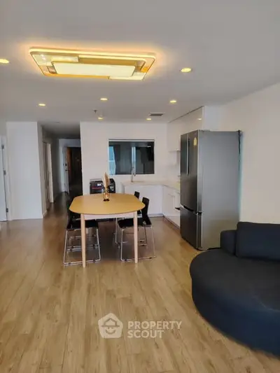 Modern open-plan living room with sleek kitchen and dining area, featuring stylish lighting and contemporary furniture.