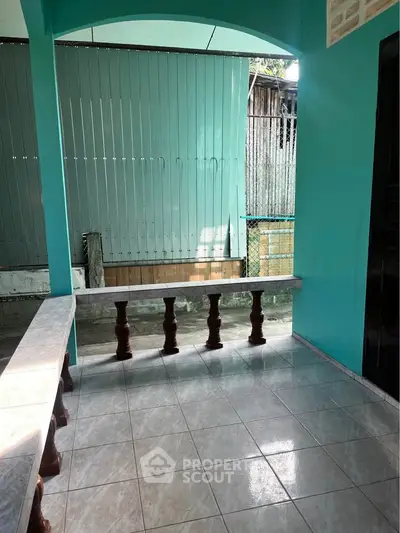 Charming covered patio with turquoise walls and tiled flooring, perfect for relaxation and outdoor gatherings.