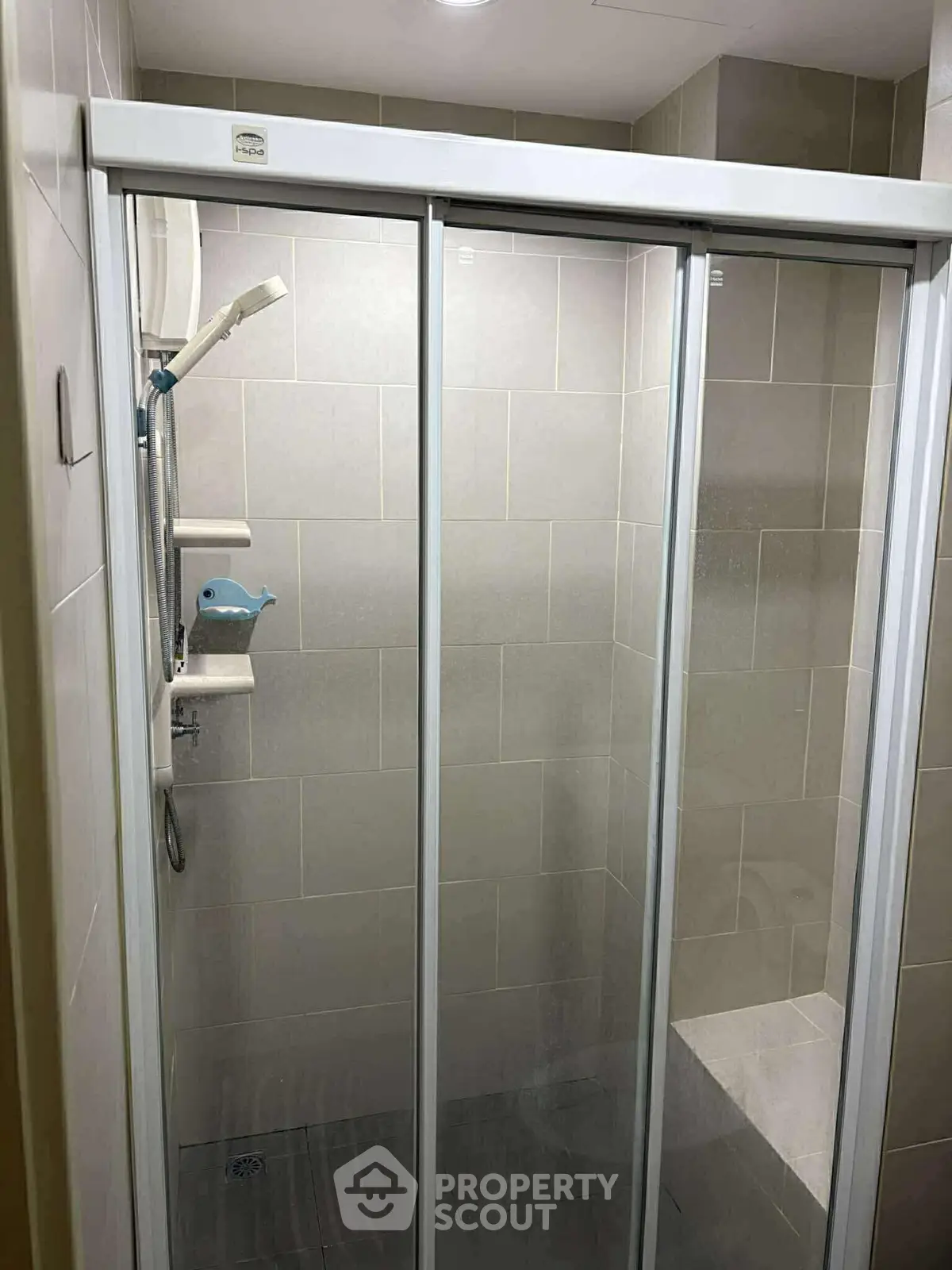 Modern bathroom with glass shower enclosure and tiled walls.