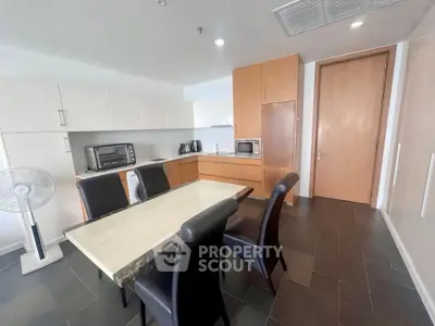Modern kitchen with sleek cabinetry and dining area, featuring contemporary appliances and elegant design.