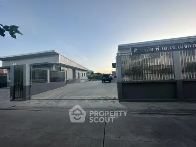 Industrial warehouse exterior with gated entrance and spacious driveway