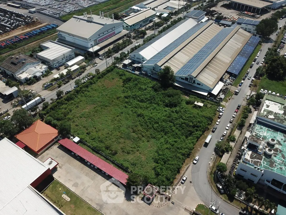 Aerial view of industrial area with large green plot and surrounding warehouses.