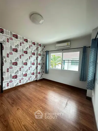 Spacious bedroom with stylish wallpaper and large window offering natural light.