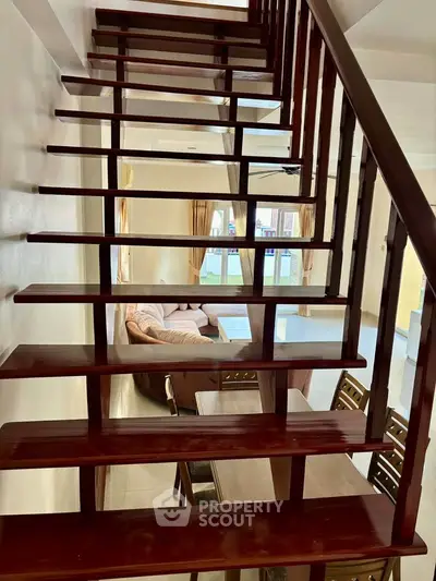 Modern wooden staircase leading to a cozy living room with elegant furniture.