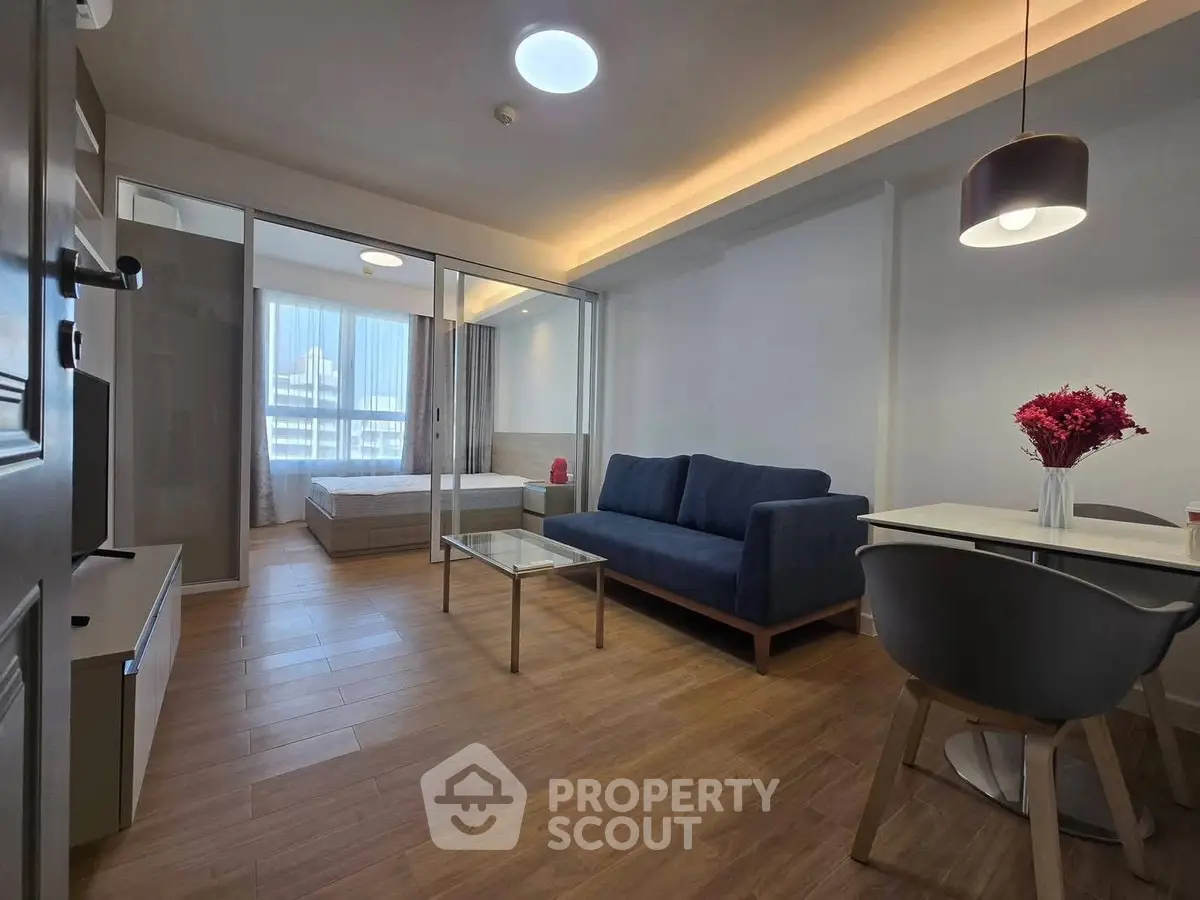 Modern open-plan living room with cozy seating and dining area, featuring stylish decor and natural light.
