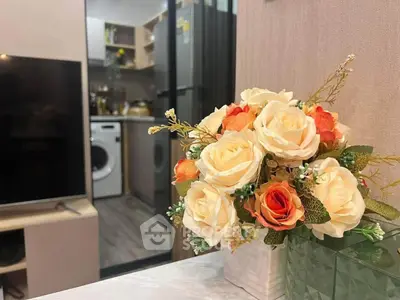 Charming living room with elegant floral decor and view into modern kitchen with appliances.