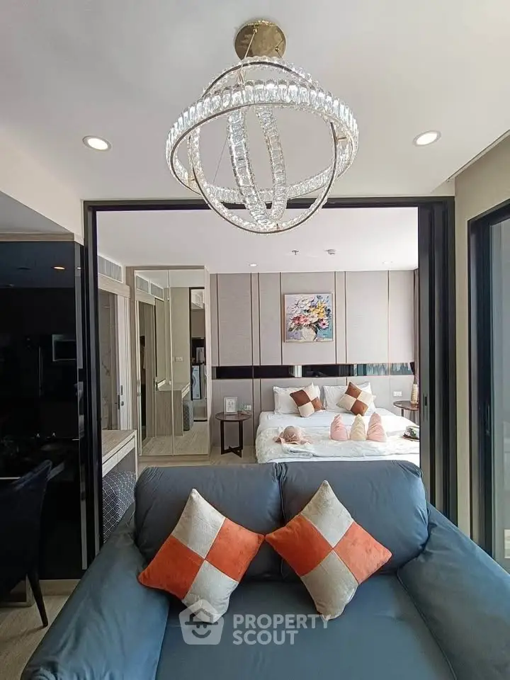 Luxurious modern living room with elegant chandelier and cozy bedroom view.