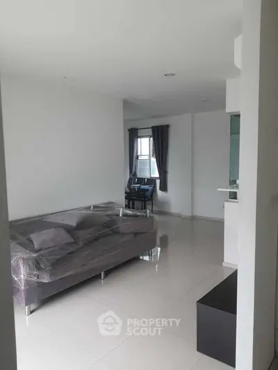 Modern living room with sleek gray sofa and dining area in open layout apartment.