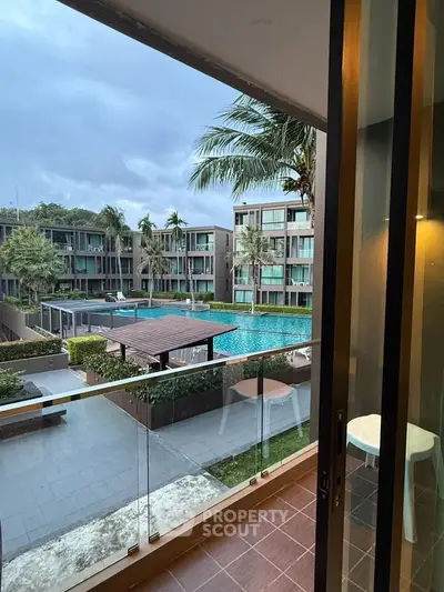 Luxurious balcony view overlooking a serene pool and modern apartment complex, perfect for relaxation.