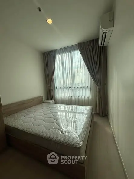 Cozy bedroom with natural light and modern air conditioning unit, perfect for restful nights.