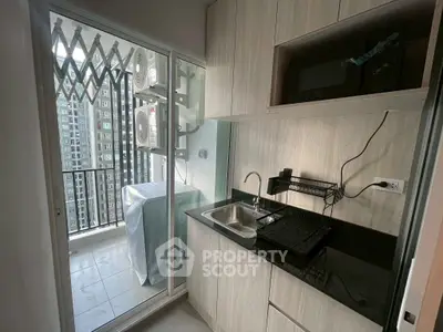Modern kitchen with balcony view, featuring sleek cabinetry and compact appliances.
