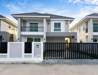 Modern two-story house with sleek design and gated entrance in a suburban neighborhood.
