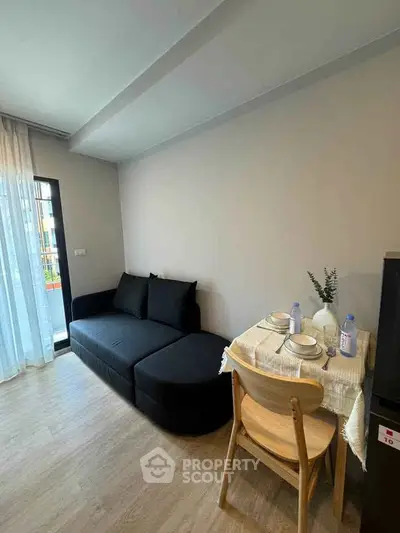 Cozy living room with modern black sofa and dining area in stylish apartment