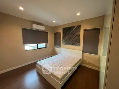 Modern bedroom with minimalist design, featuring a large bed and natural light from windows.