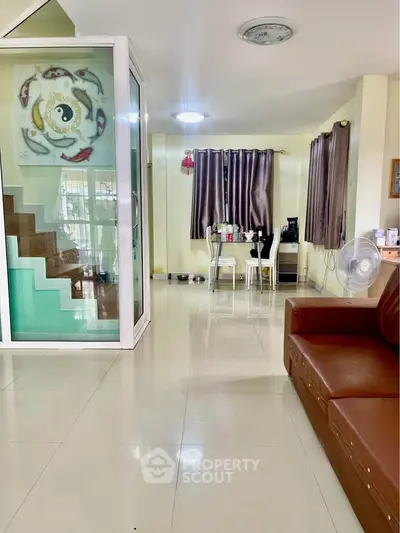 Spacious living room with modern decor and dining area, featuring a unique staircase design.