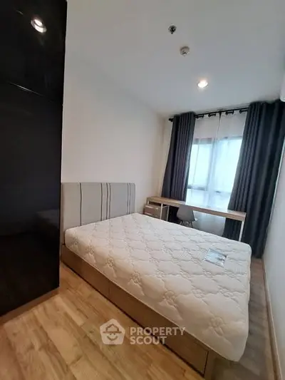 Modern bedroom with cozy bed and natural light from large window.