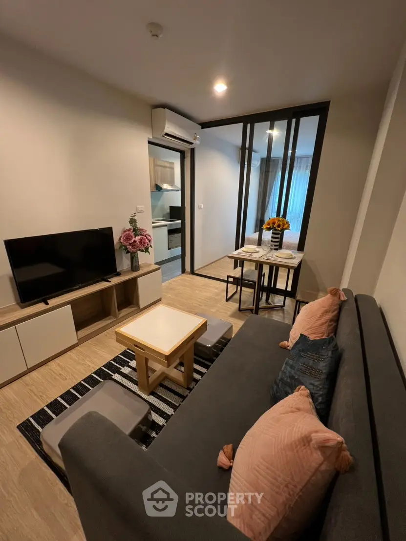Modern living room with stylish decor and open layout, featuring a cozy sofa and flat-screen TV.
