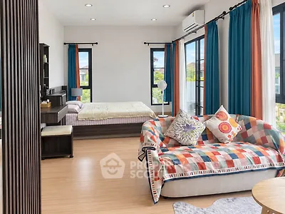 Spacious bedroom with vibrant decor and large windows offering natural light