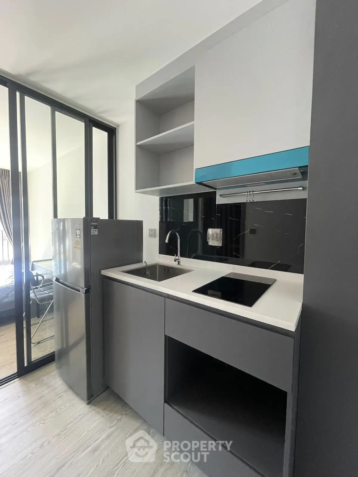 Modern compact kitchen with sleek design and glass partition, featuring built-in appliances and ample storage.