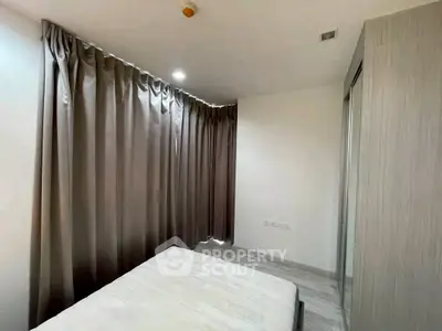 Cozy bedroom with large window and modern curtains, perfect for relaxation.